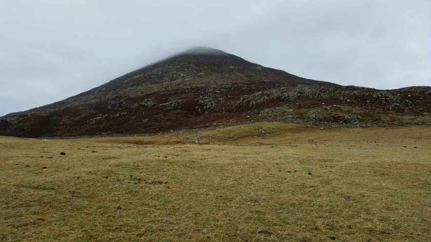 A dry brown mountaintop capped with clouds