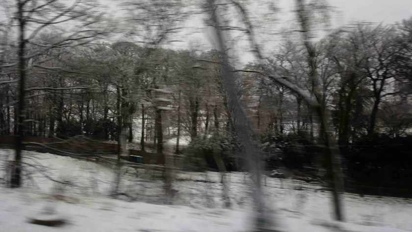 A blurry view of a snow covered country landscape.