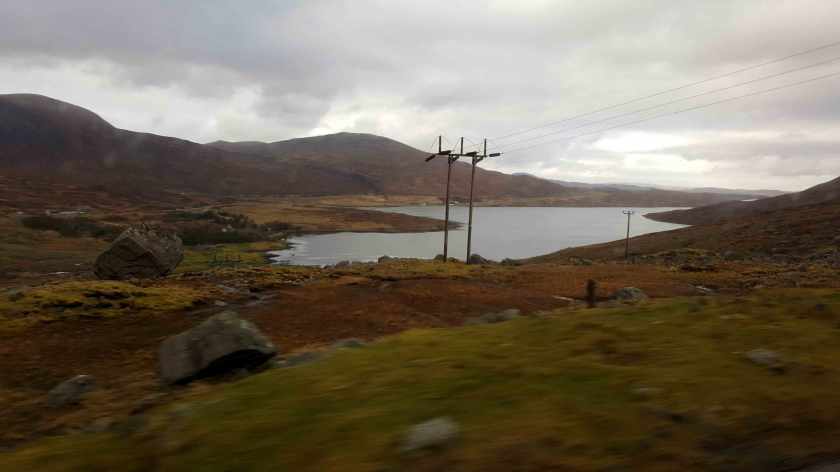 Telegraph poles at the edge of a bay in an orangey landscape.