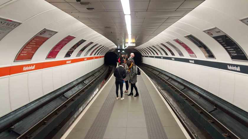 The curved ceiling envelopes passengers as they stand on the subway platform.