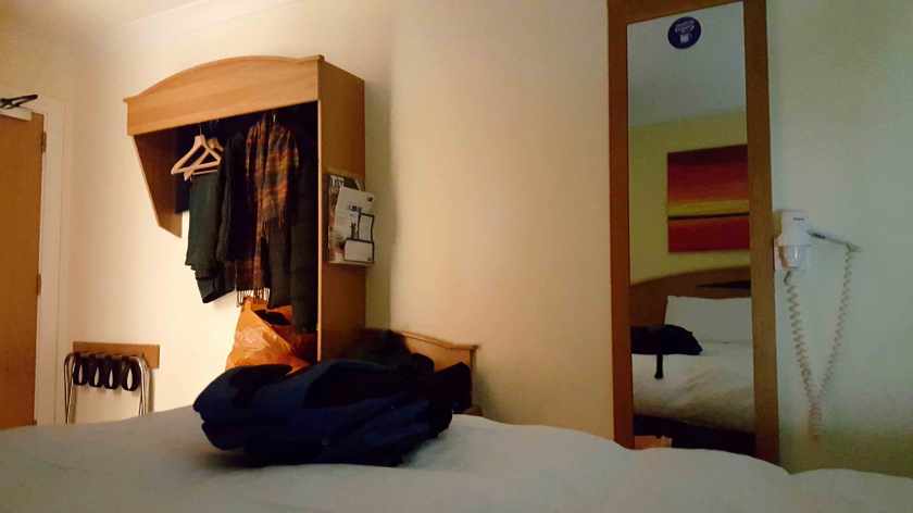 A rucksack lies at the edge of a hotel bed.