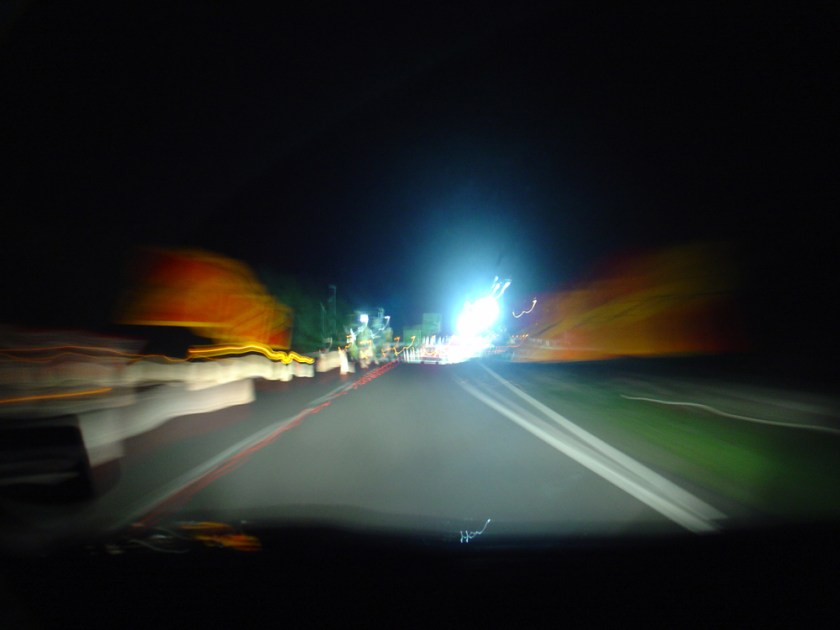 Bright lights flare at the end of a motorway at night