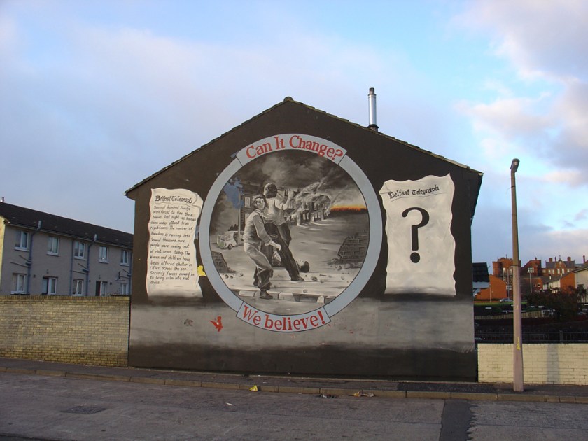 A mural showing children throwing grenades and the words Can it Change, We believe painted on the side of a house