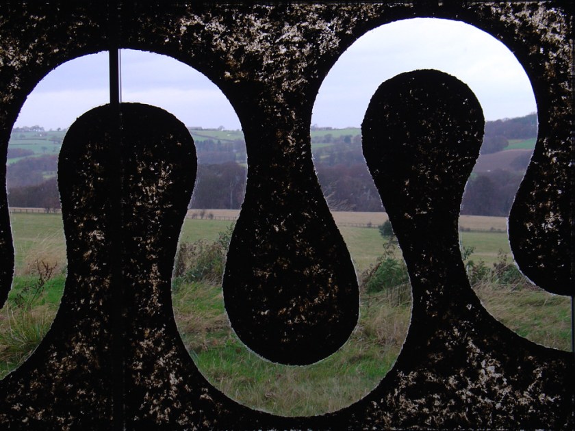 A serpentine shape in an otherwise dirty window reveals the field and hills beyond