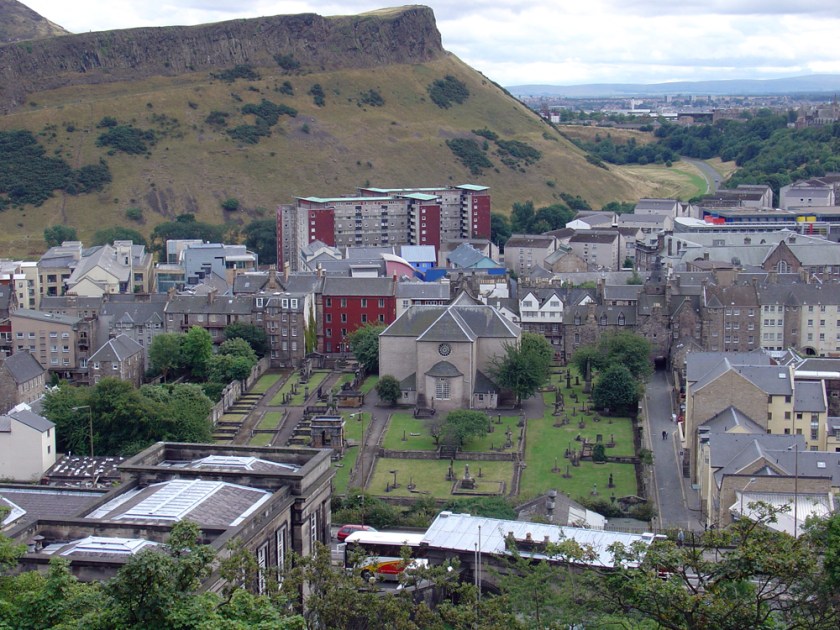 Old buildings sit at the foot of a low rocky peak