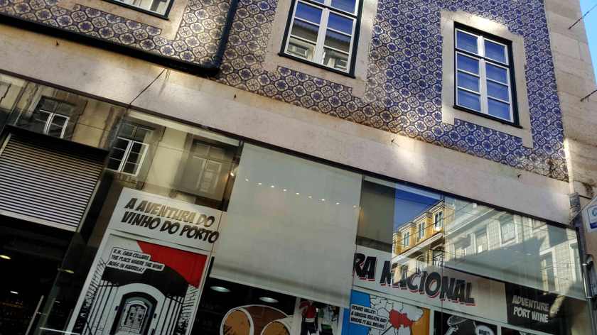 Reflections and signs contrast in the store window of a tiled commercial building