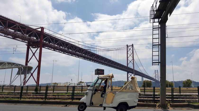 A scooter drives on the motorway under a giant steel bridge