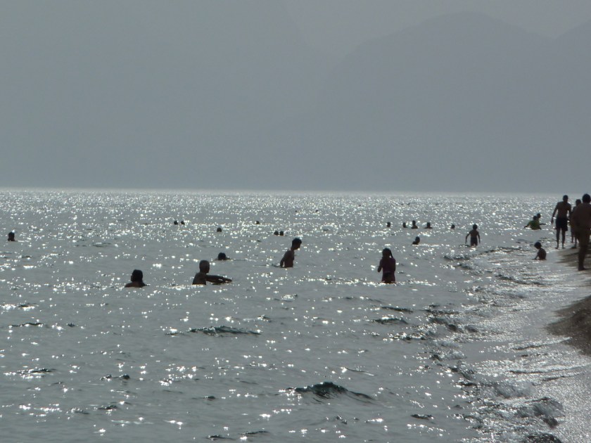 Swimmers silhouetted in the sea on a hazy day