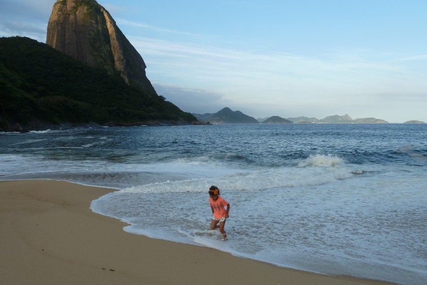 A young girl plays in the surf at the edge of a sandy beach