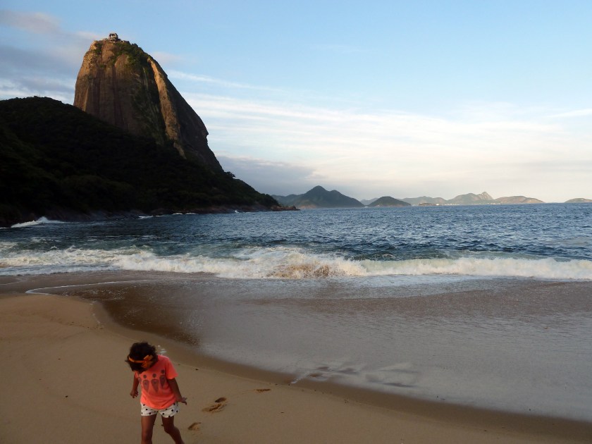 A small girl walks away from the surf on a sandy beach