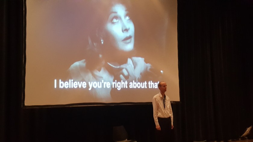 Tim stands in a white shirt before a projection of Vivien Leigh as Blanche du Bois. The subutitle reads, "I believe you're right about that."