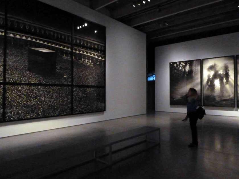 Woman stands before a large black and white photograph of the Holy Kaaba in Mecca