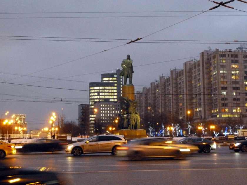 Statue of Lenin stands over busy intersection at dusk
