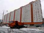 Orange dumptruck before orange and white Soveit era apartment block on snowy street