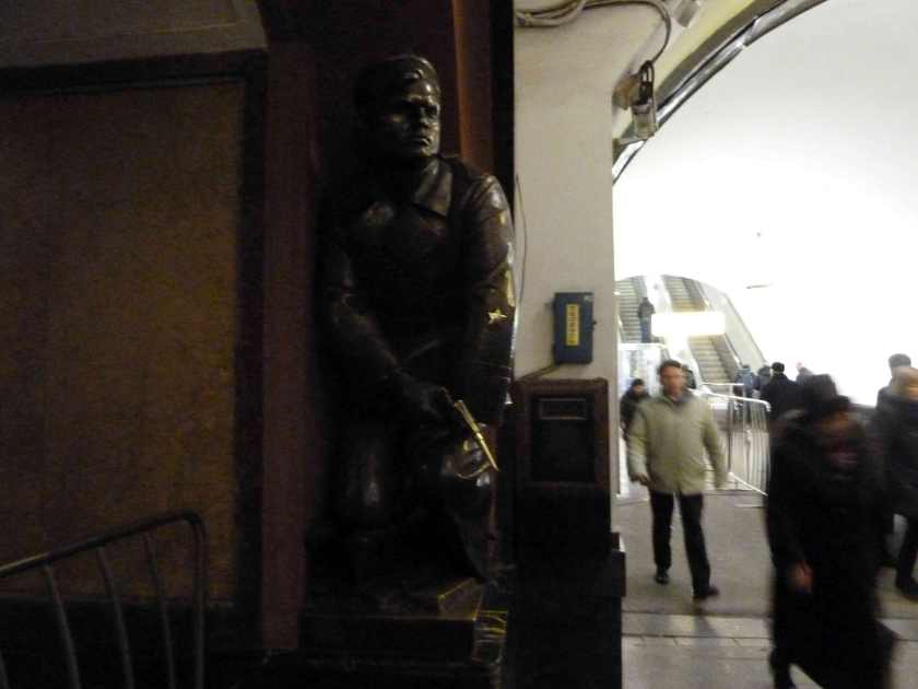 Bronze statue of officer with handgun seeing to lie in wait for unsuspecting commuter