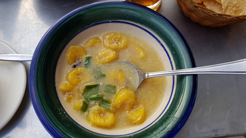 A spoon rests in a bowl of banana soup