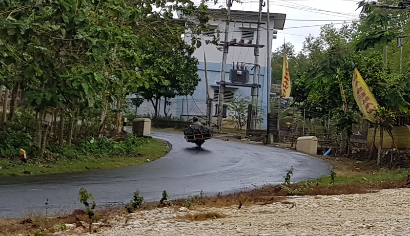 A loaded motorbike passes on a rural road