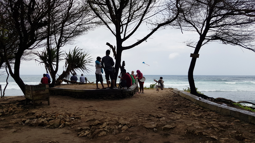 Seashore with silhouetted people in the distance and a kite flying past