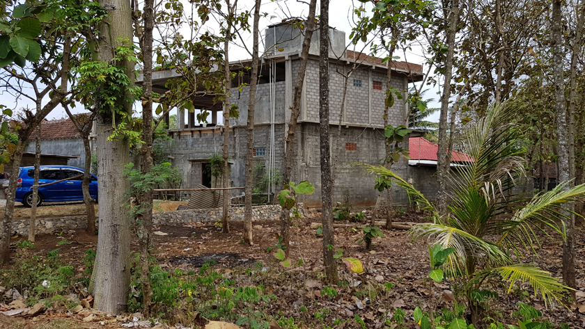 Concrete block house under construction in the middle of a forested landscape