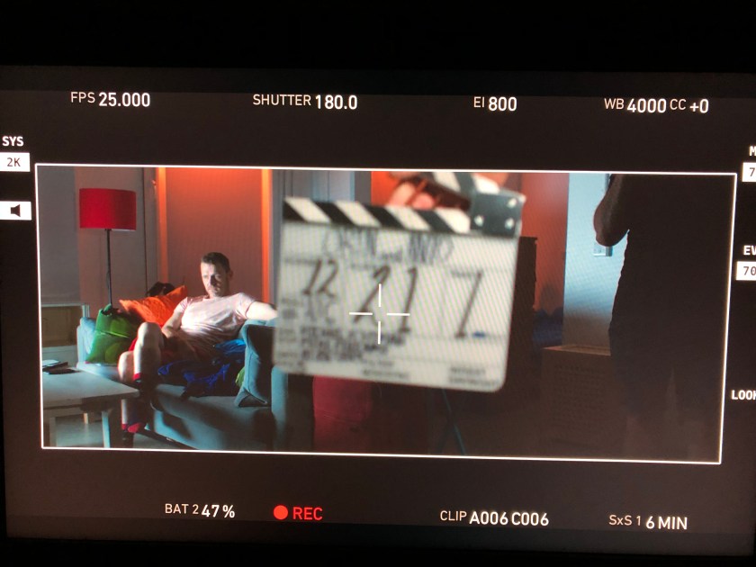 A man watches TV with a clapper board in the foreground.
