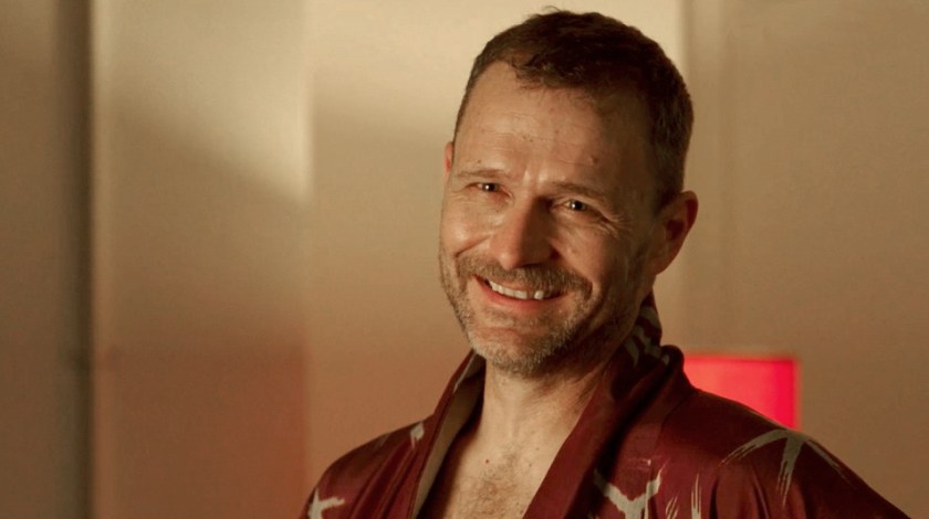 Smiling man from shoulders up, with short hair and scruffy beard