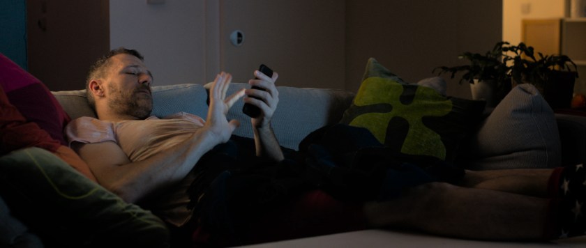 Anto on the sofa swipes his phone